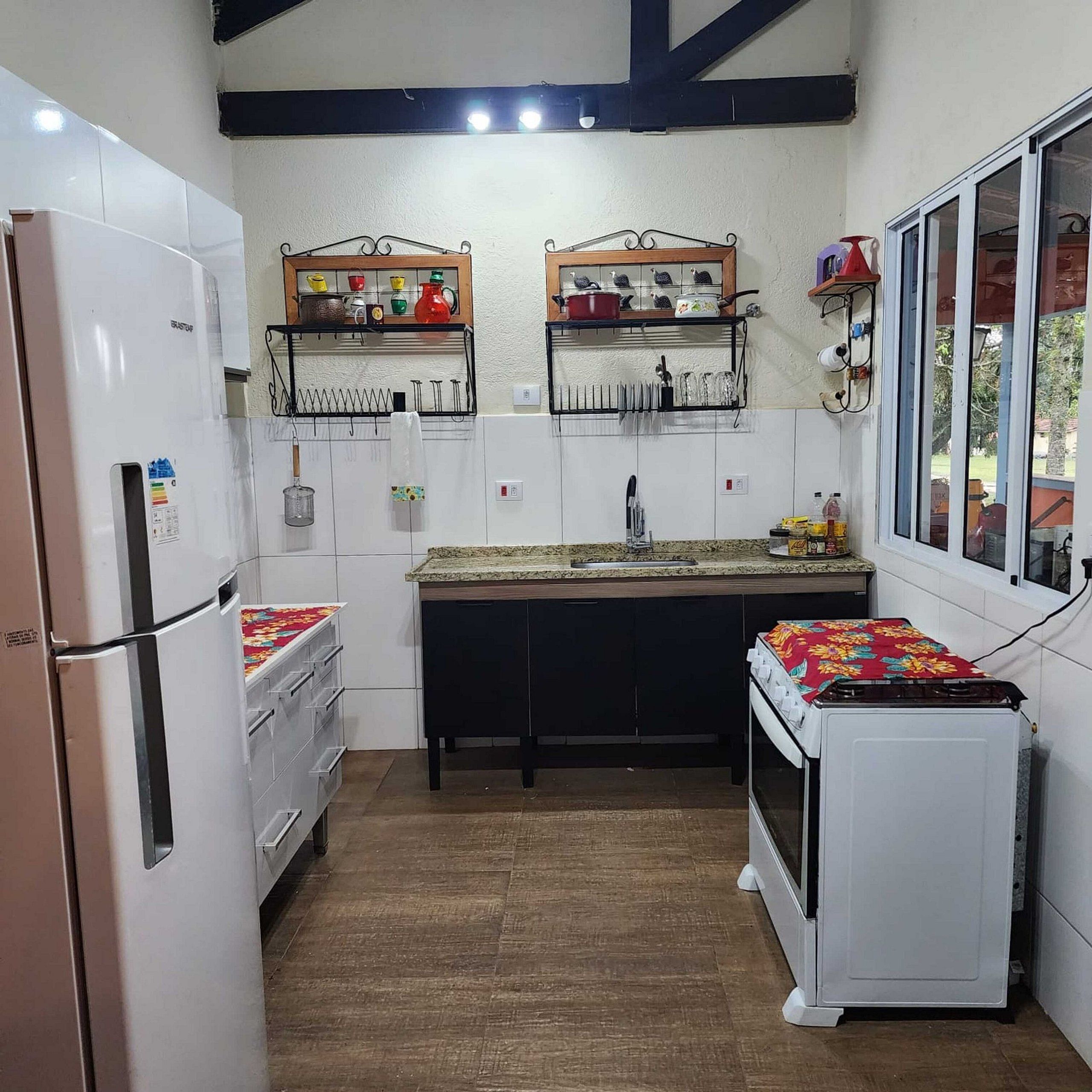 Una cocina compacta con electrodomésticos blancos, estantes de madera sobre la encimera y una ventana con vistas.