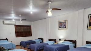 A hotel room with four single beds, a ceiling fan, a window with wooden shutters, and a wall-mounted air conditioner. - Magnífico Rancho em Jarinu (Jarinu)