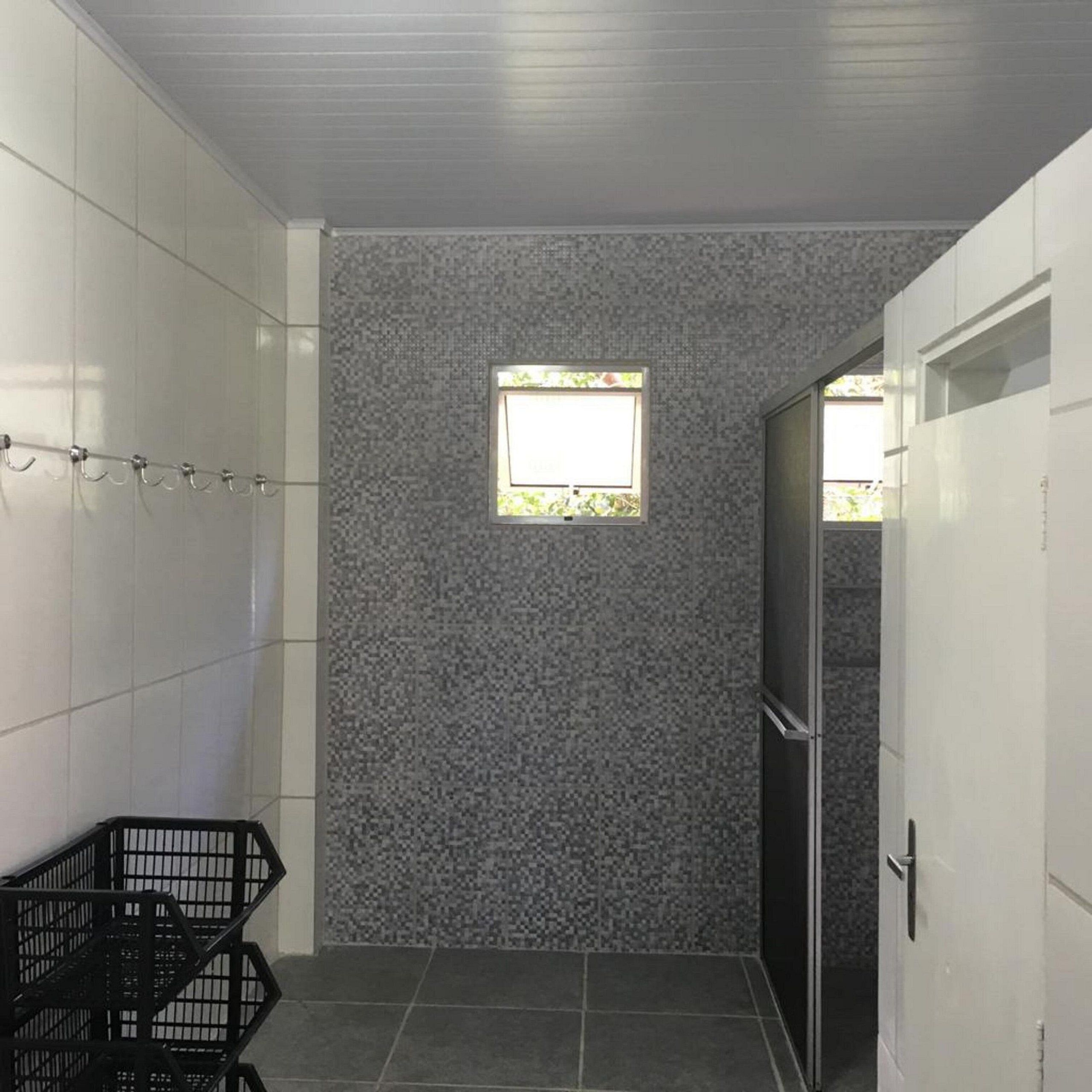 Un pasillo estrecho con paredes de baldosas, una ventana pequeña y una silla de metal negro.