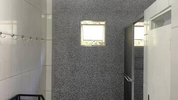 Un pasillo estrecho con paredes de baldosas, una ventana pequeña y una silla de metal negro.