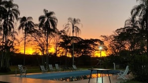 A swimming pool area with lounge chairs and a sunset in the background. - Magnífico Rancho em Jarinu (Jarinu)