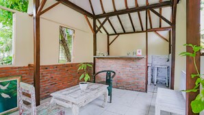 Un patio rústico al aire libre con una mesa y sillas de madera, un muro de ladrillo y un suelo de baldosas.