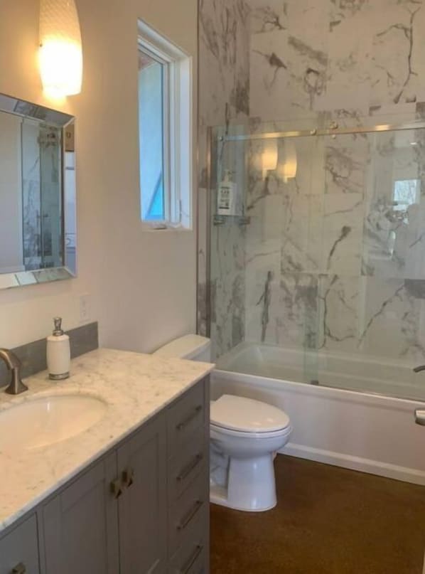 A bathroom with a marble sink, a toilet, and a glass-enclosed shower.