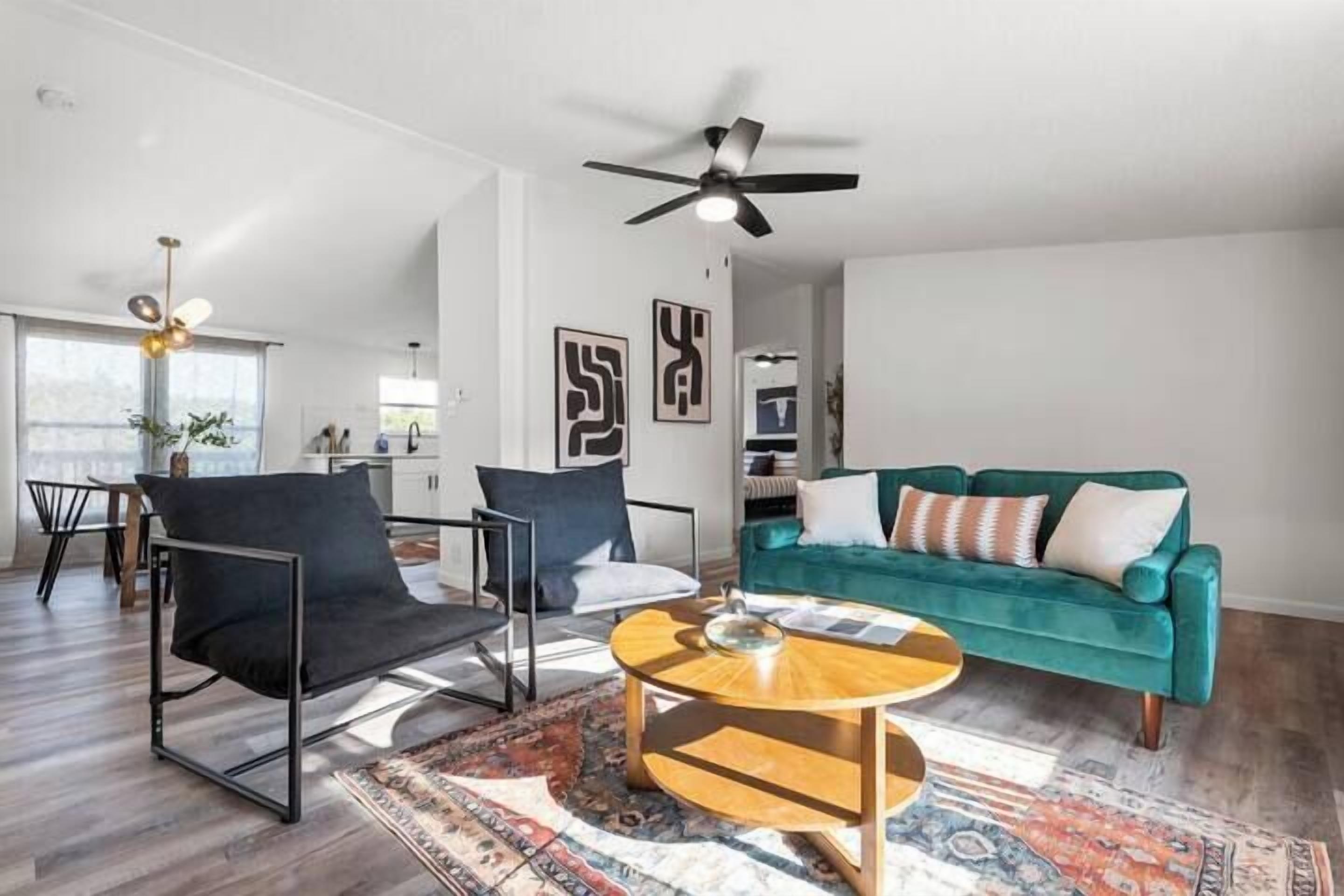 A modern living room with a teal sofa, black armchair, and a round coffee table.