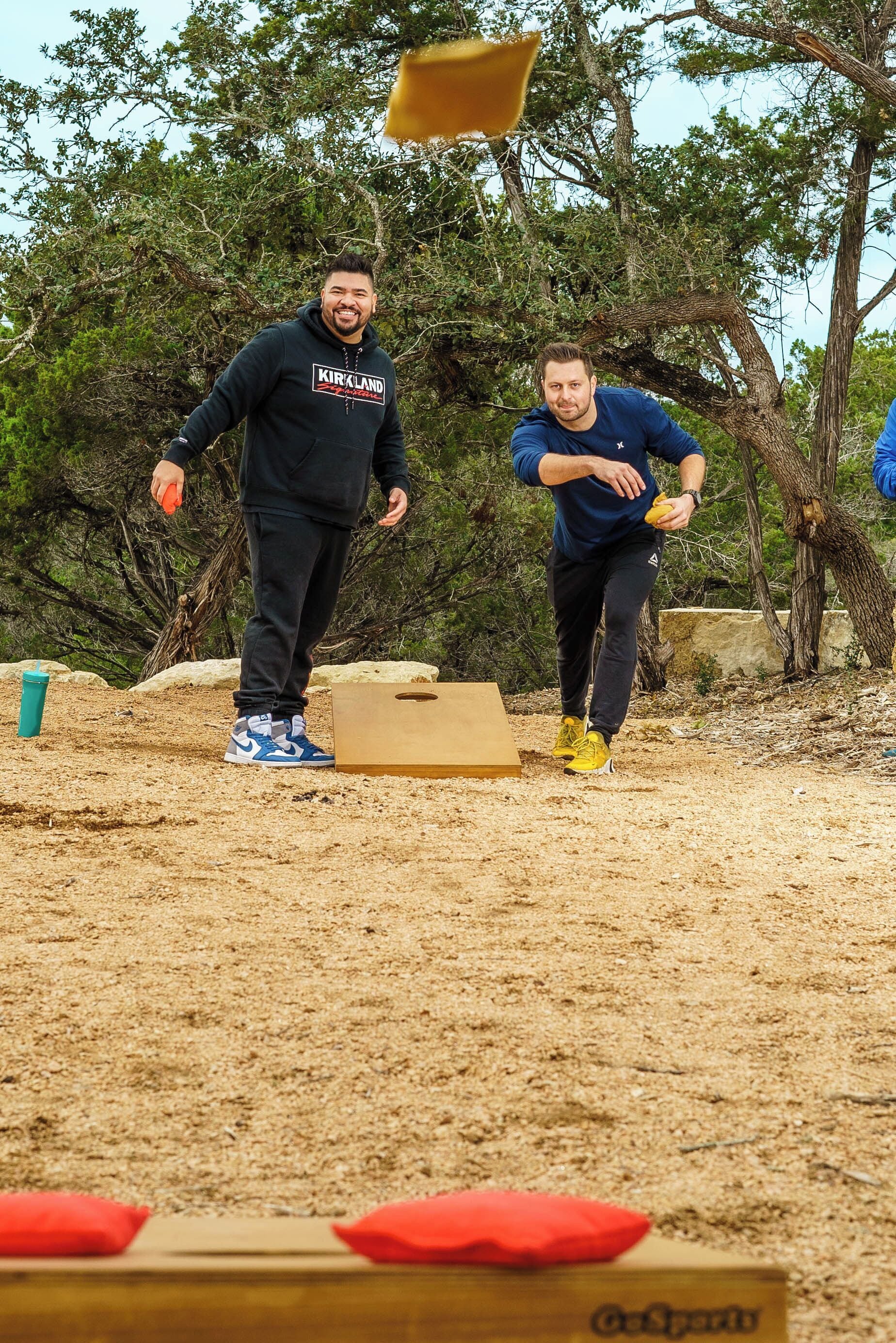 Two people playing a game outdoors with a box and a yellow object.