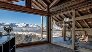 Ein Holzinnenraum mit großen Fenstern und Blick auf die Berge.
