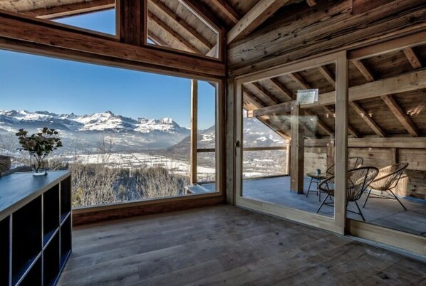 A wooden interior with large windows offering a mountain view.