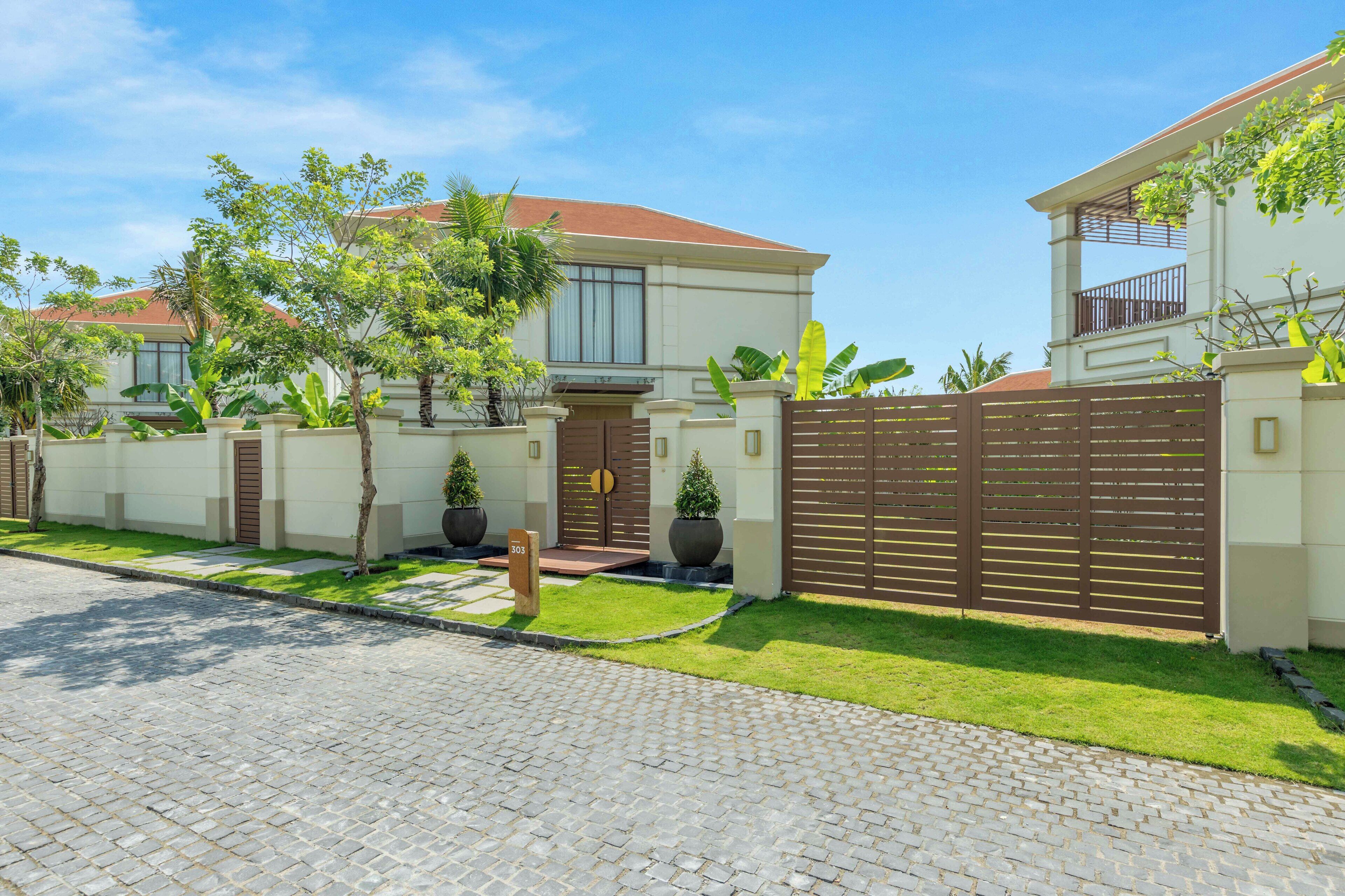A residential property with a paved driveway, a gated entrance, and a well-maintained lawn.