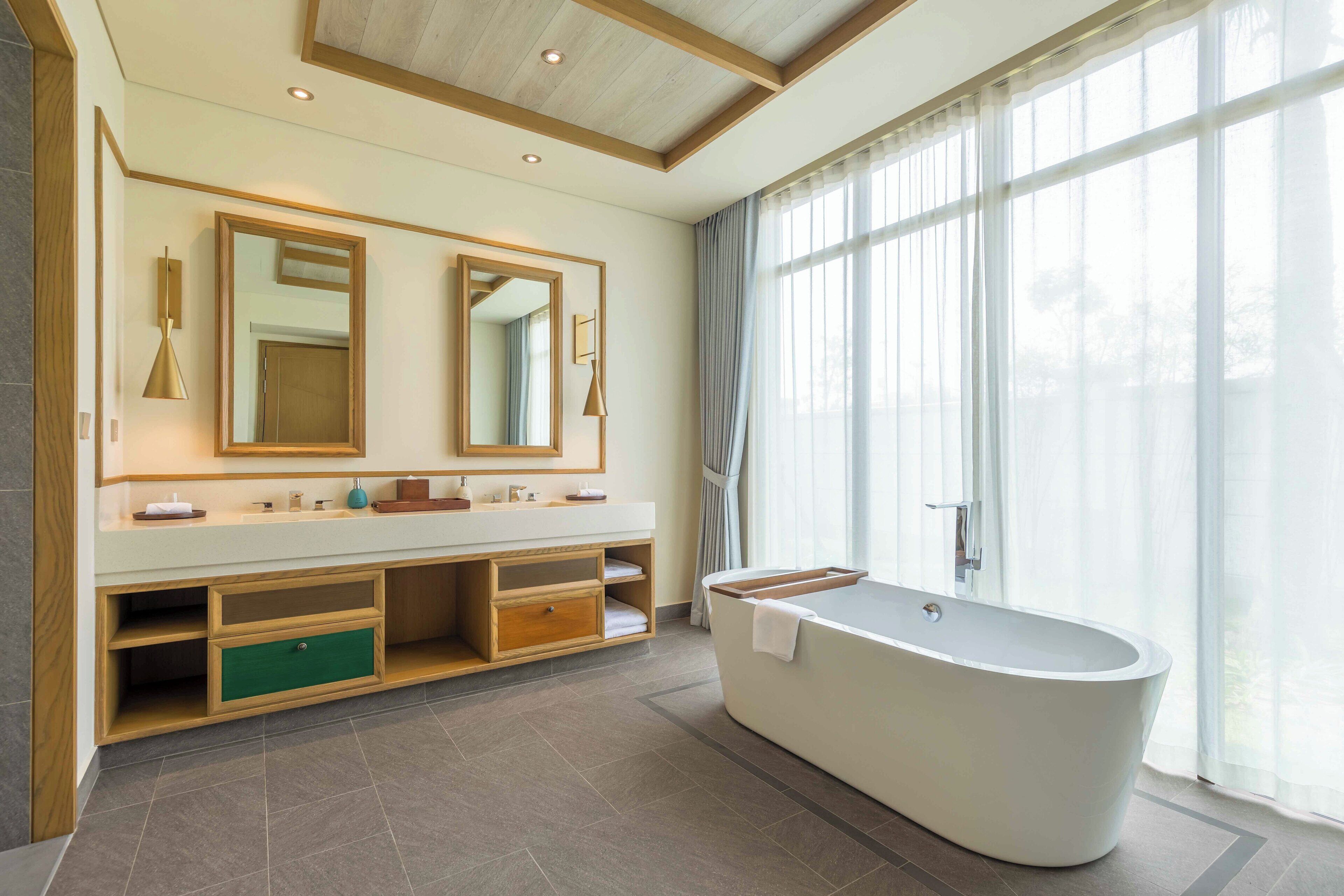 A modern bathroom with a freestanding bathtub, a large mirror, and a vanity with open shelving.
