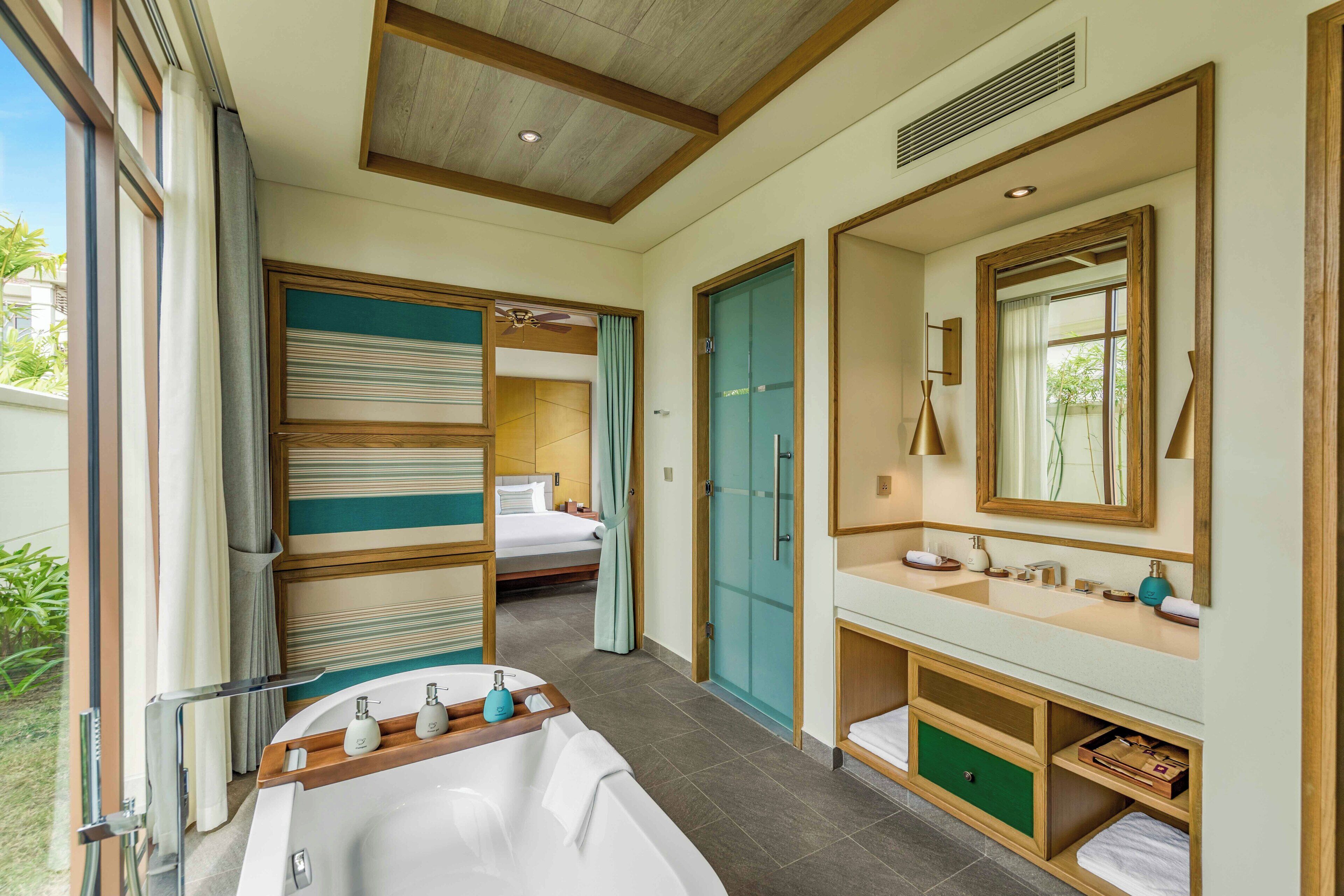 A modern bathroom with a bathtub, vanity, and a large mirror.