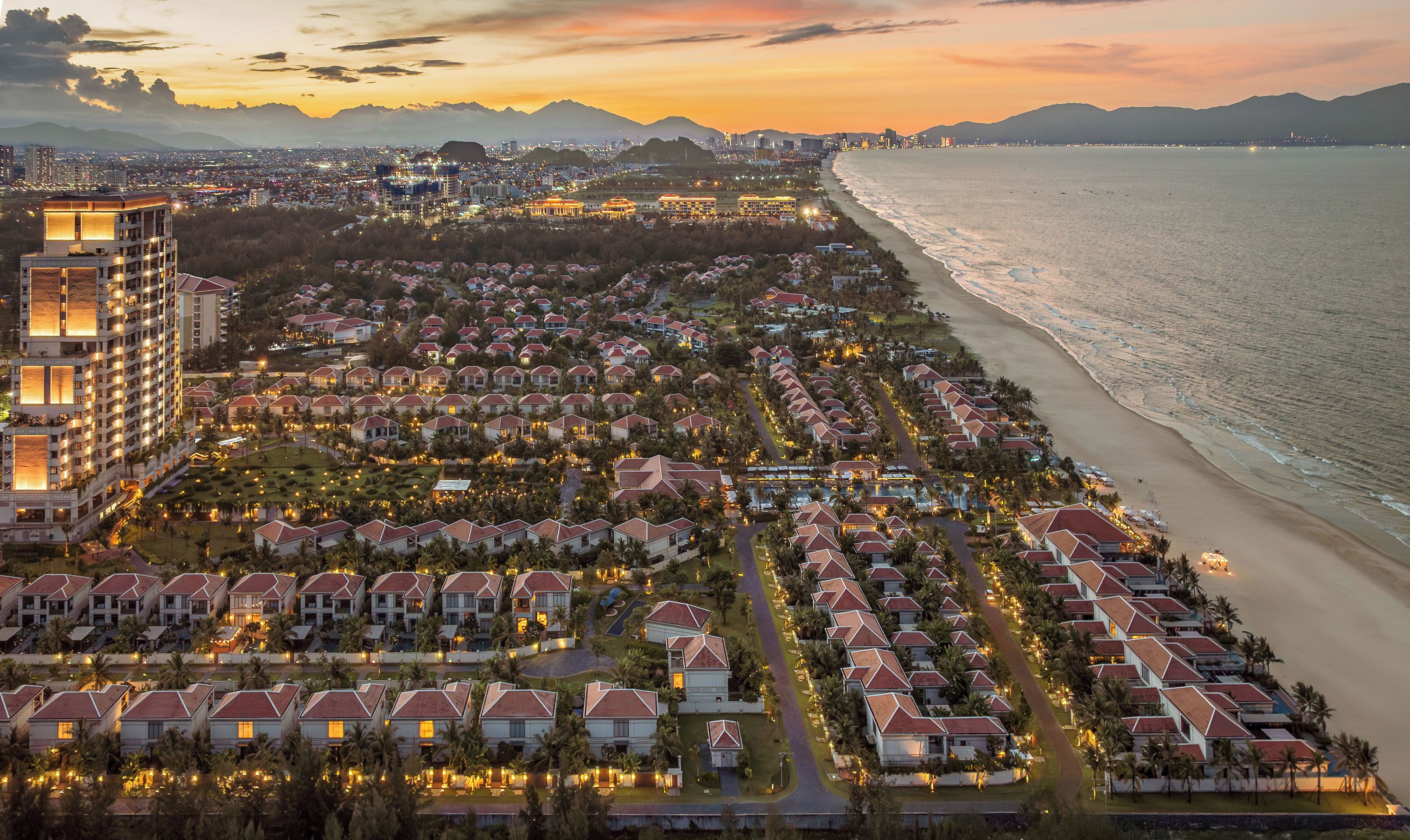 A coastal resort with beachfront villas, a central road, and a large hotel.