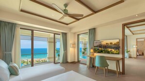 A hotel room with a large bed, a desk, and a view of the ocean. - Fusion Resort & Villas Da Nang (Da Nang)
