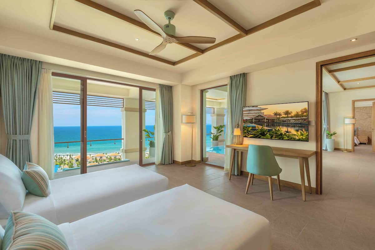 A hotel room with a large bed, a desk, and a view of the ocean.