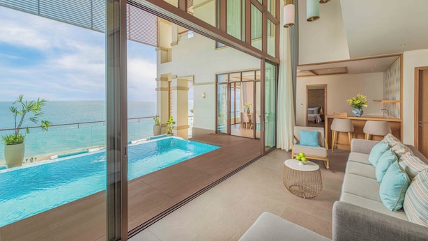 A modern living area with a pool, large windows, and a view of the sea. - Fusion Resort & Villas Da Nang (Da Nang)