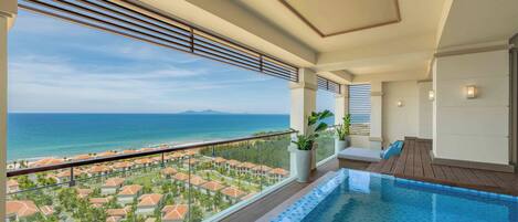 A balcony with a pool, overlooking a resort area and the sea.