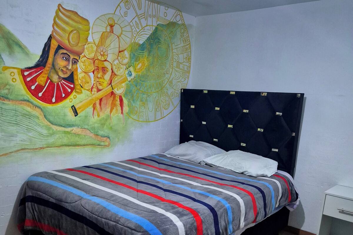 A bedroom with a bed, a nightstand, a wall mural, and patterned floor tiles.