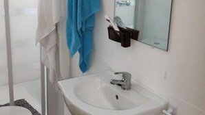 A bathroom with a white sink, a mirror, and a towel rack with two towels. - M&m Apartament (Madrid)