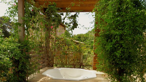 A wooden pergola with a hot tub under it, surrounded by lush greenery and steps leading up to the hot tub. - Refúgio da Ibiraquera Jacuzzi e Vista (Imbituba)