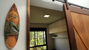 A room with a sliding door, a window with a view of greenery, and a wall-mounted decorative piece. - Refúgio da Ibiraquera Jacuzzi e Vista (Imbituba)