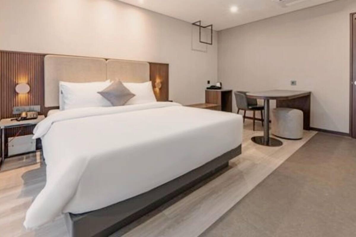 A modern hotel room with a large bed, bedside tables, a desk, and a chair.