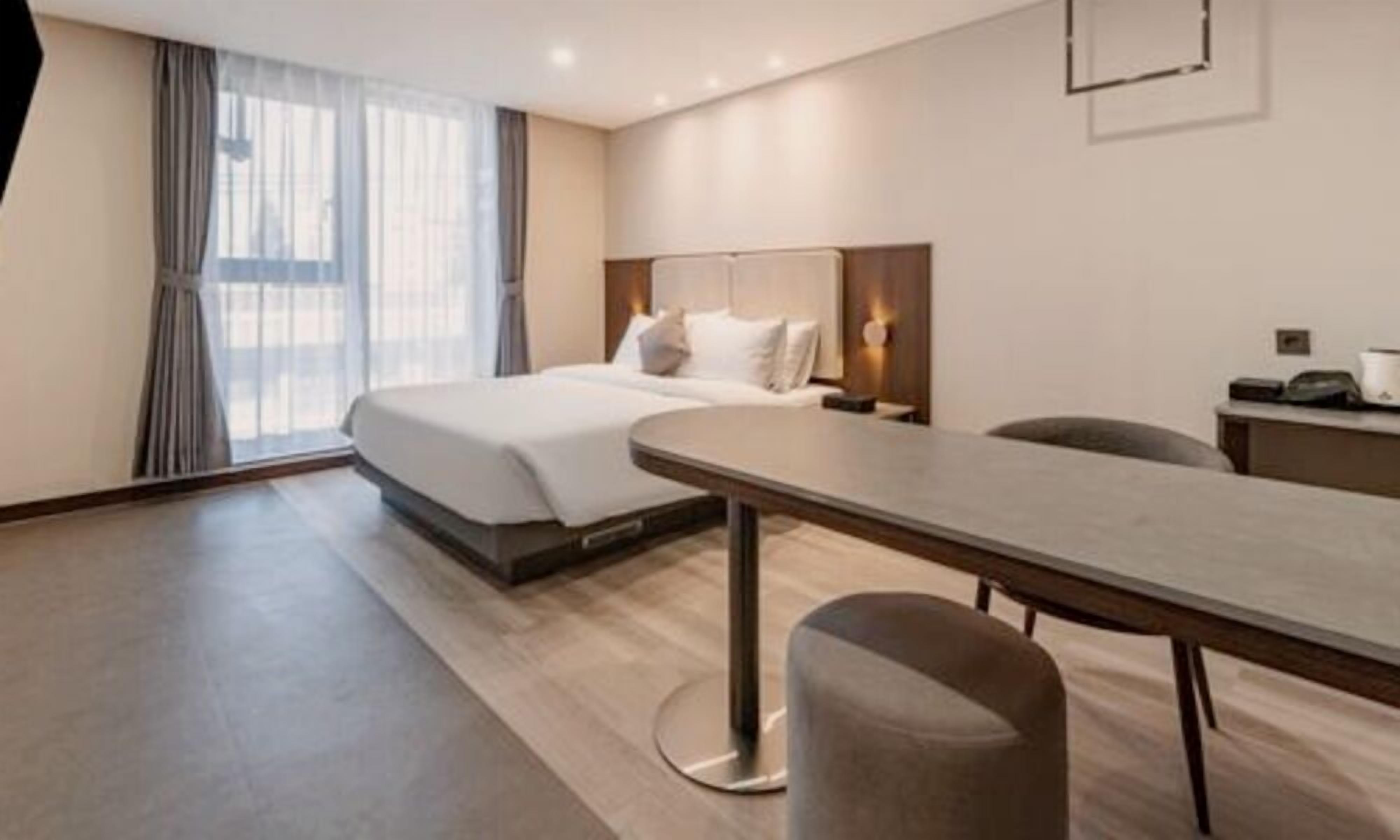 Una habitación de hotel moderna con una cama grande, un escritorio y una silla.