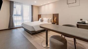 Una habitación de hotel moderna con una cama grande, un escritorio y una silla.