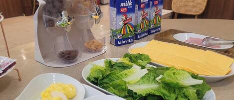 A table with various food items including scrambled eggs, a creamy dish, fresh lettuce, and cheese.