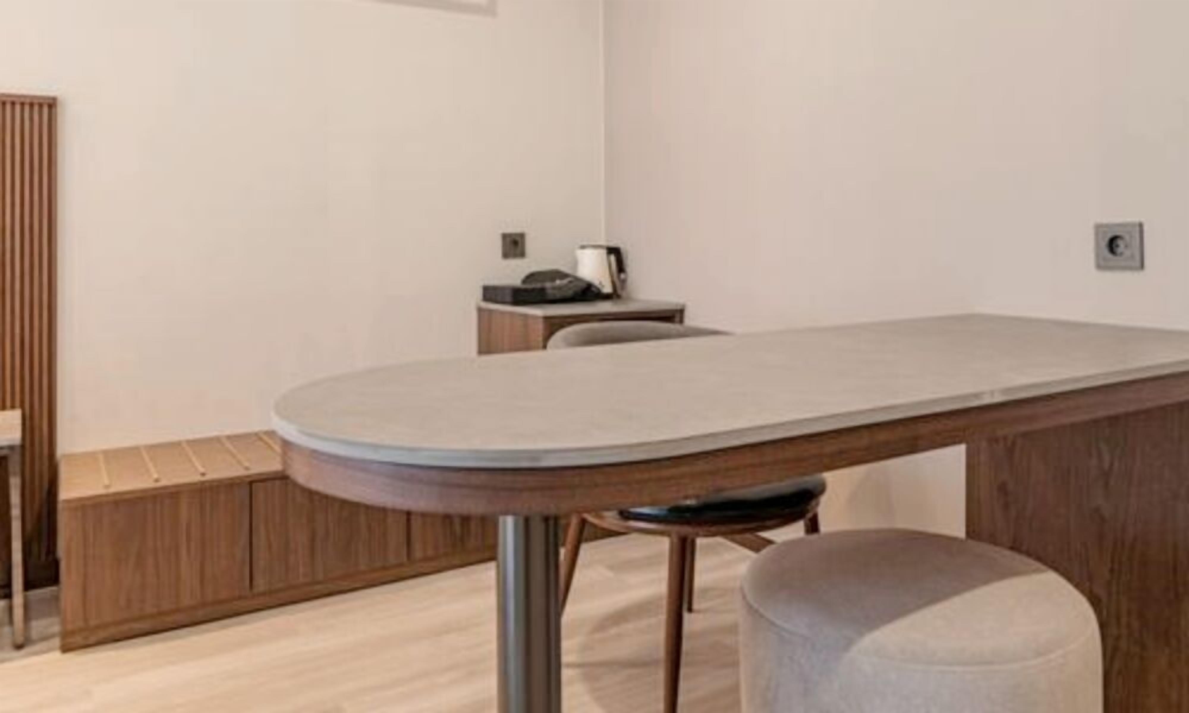 Une pièce moderne avec un plancher en bois, une table ronde au plateau gris et un tabouret rembourré de couleur grise.
