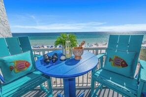 A turquoise deck with a table, chairs, and a bottle of champagne. - 🌊Islander 502 - The Sea Glass Studio | Gulf Views | Pool🌊 (Fort Walton Beach)
