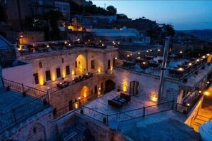 A courtyard with stone buildings, outdoor seating, and a flagpole. - Ağa Konağı (Mardin)
