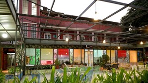 A covered outdoor seating area with metal chairs and tables, surrounded by potted plants. - Golden Days Resort and Spa (Jaipur)