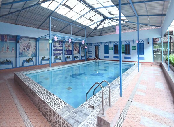 Swimmers can enjoy the pool surrounded by a walkway and ceiling supported by metal beams.