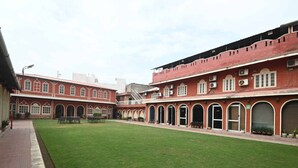 A courtyard with a red brick building featuring arched doorways and a central staircase. - Golden Days Resort and Spa (Jaipur)
