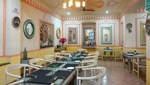 A dining area with multiple tables and chairs, decorative mirrors, and a ceiling fan. - Golden Days Resort and Spa (Jaipur)