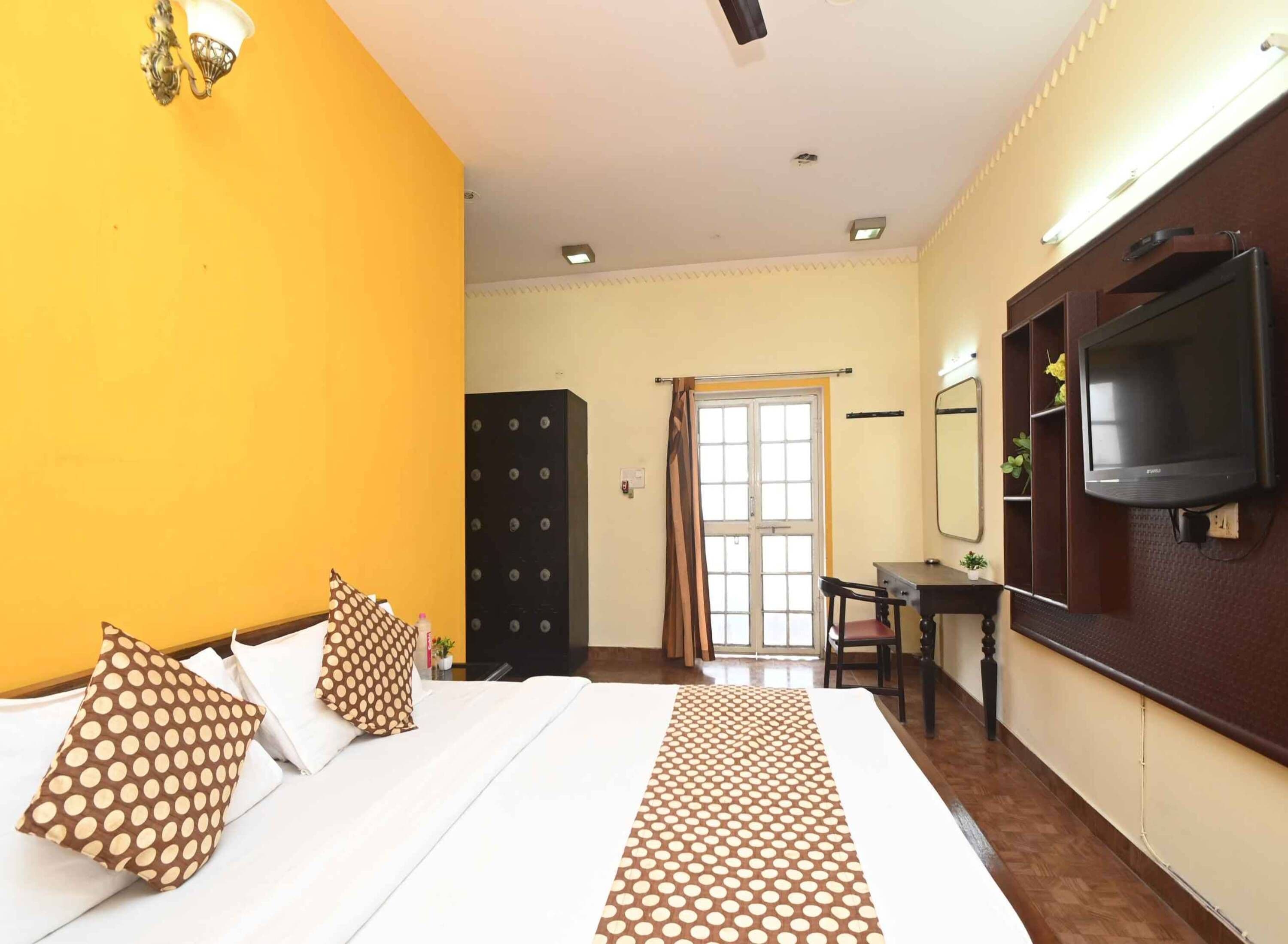 Une chambre d’hôtel équipée d’un lit, d’un bureau, d’une télévision et d’une armoire.