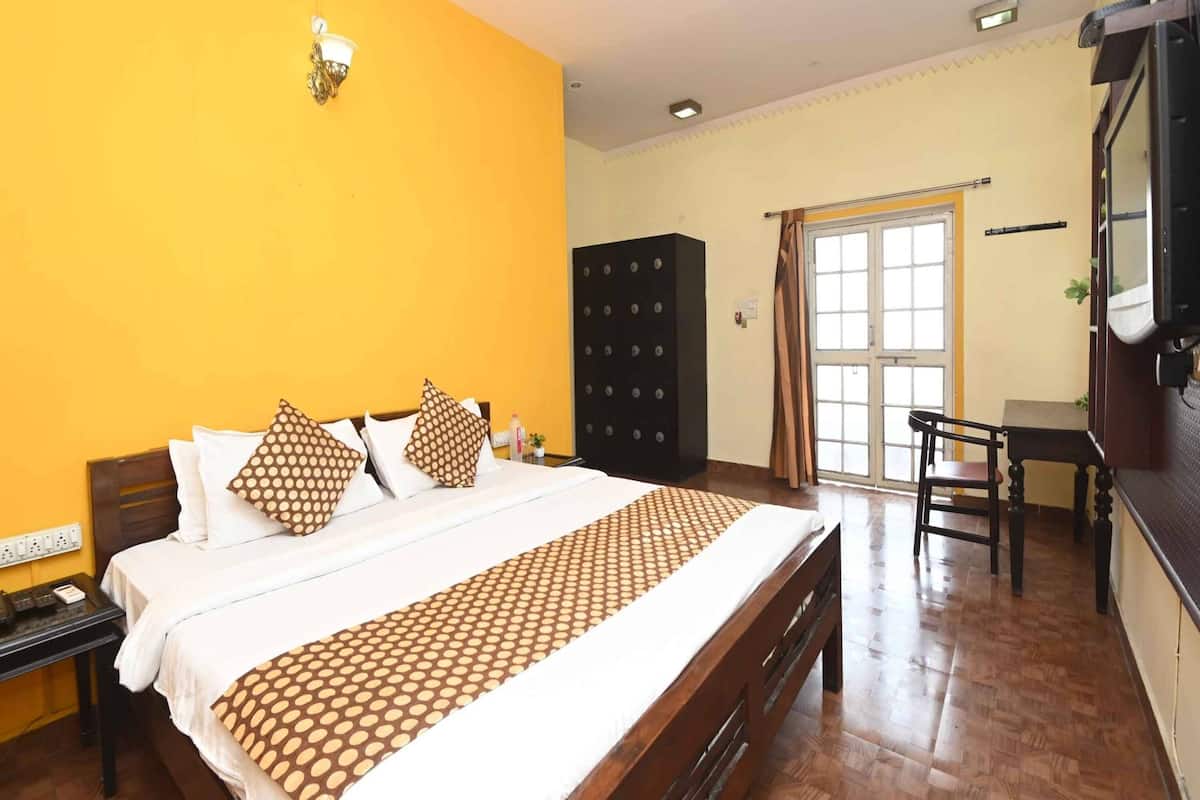 A hotel room with a bed, a wardrobe, a desk, and a television.