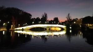 Un pont dont les lumières se reflètent sur l’eau au crépuscule.