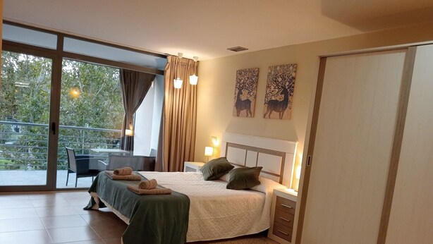 Une chambre moderne avec un grand lit, un bureau et un balcon.