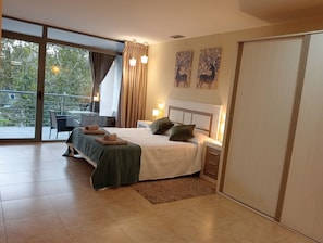 Une chambre moderne avec un grand lit, un bureau et un balcon.