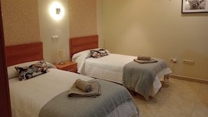 Une chambre d’hôtel avec deux lits, chacun doté d’une tête de lit, d’une table de chevet, d’une lampe et d’un tableau encadré au mur.