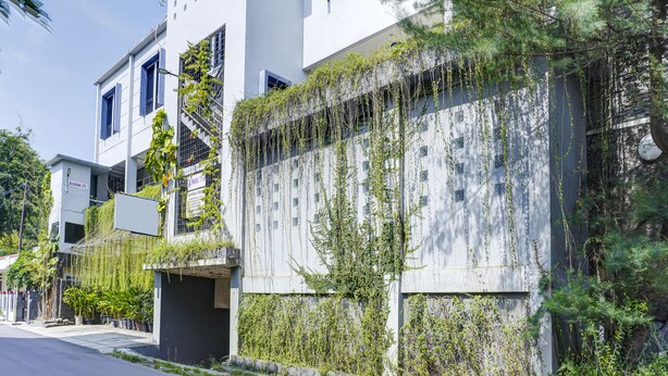 Ein modernes Gebäude mit heller Fassade, zahlreichen Fenstern und einem überdachten Eingang.