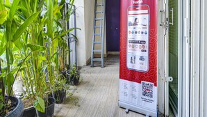 Ein Flur mit Topfpflanzen, einer Leiter und einem Werbeplakat für OYO Rindang Guesthouse Syariah.