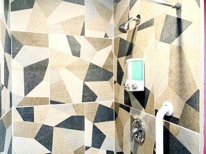 A bathroom with geometric patterned tiles, a handheld showerhead, a handheld showerhead with a digital display, and a wall-mounted faucet. - Somerset  (San Diego)