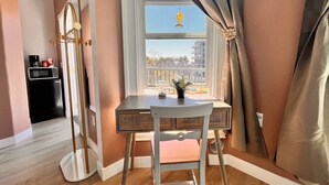 Una habitación con una mesa de comedor y una silla, una ventana con cortinas, y vistas a edificios.