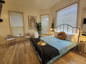 A bedroom with a bed, a desk, a chair, and a potted plant. - Somerset  (San Diego)