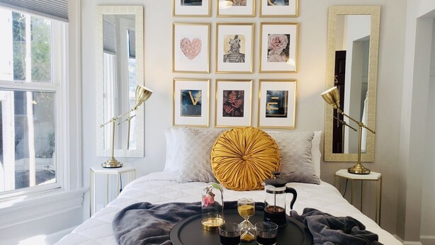 Un dormitorio ordenado con cama, mesitas de noche, cafetera y una bandeja con tazas y tetera.