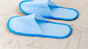 Un par de pantuflas azul claro con ribete azul sobre una superficie blanca y mullida.