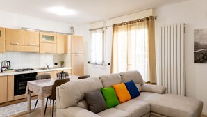 Una cocina moderna con armarios de madera, una mesa de comedor y un sofá color crema con cojines de colores.