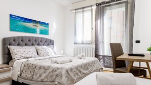 Un dormitorio con cama, una silla, una mesa y un cuadro en la pared.