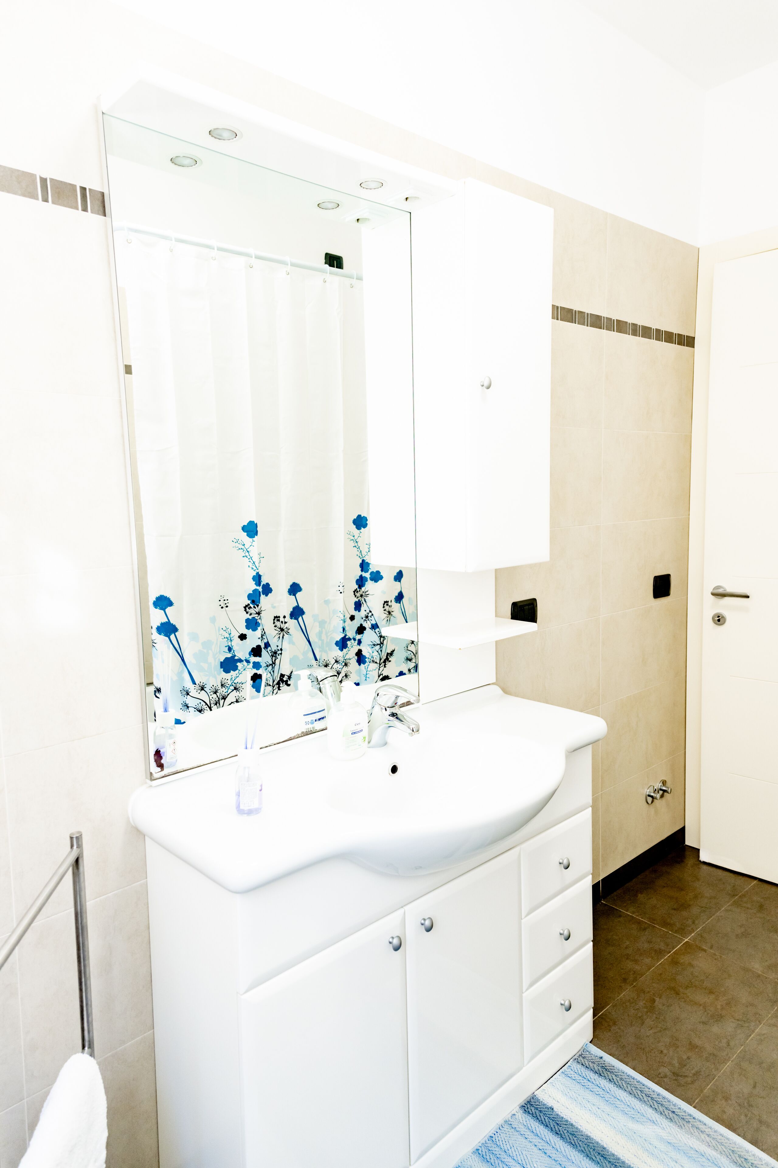 A bathroom with a white sink, mirror, and cabinet.